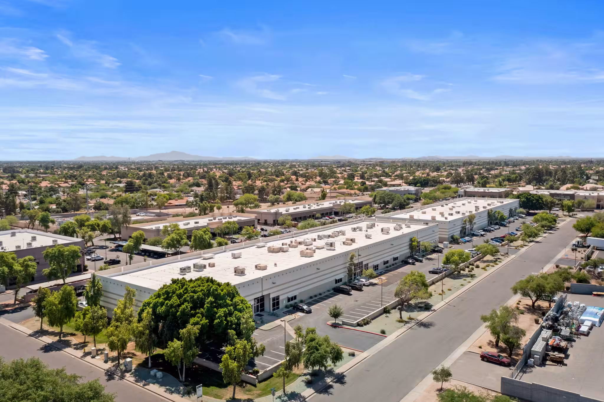 Aerial photo of a long warehouse with trees and small mountains on the horizon