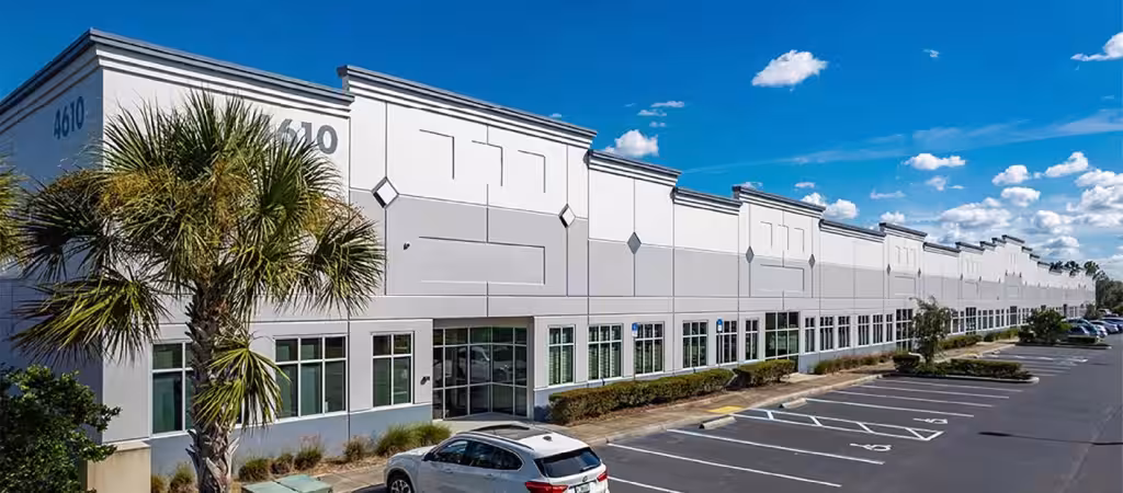 Warehouse front entrance with a parking lot and palm trees